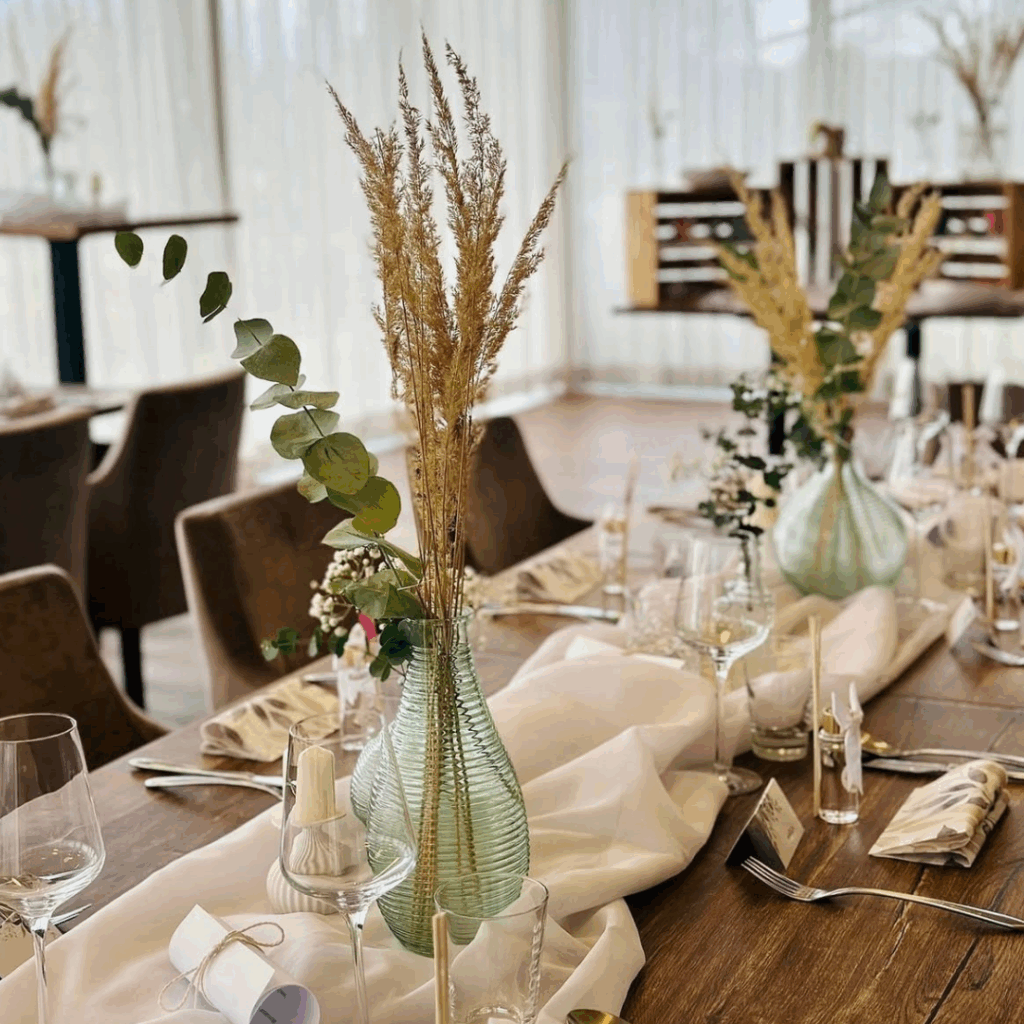 Festlich gedeckter Tisch mit Glasvasen, Trockenblumen und eleganter Tischdekoration im Restaurant Birdie in Wels