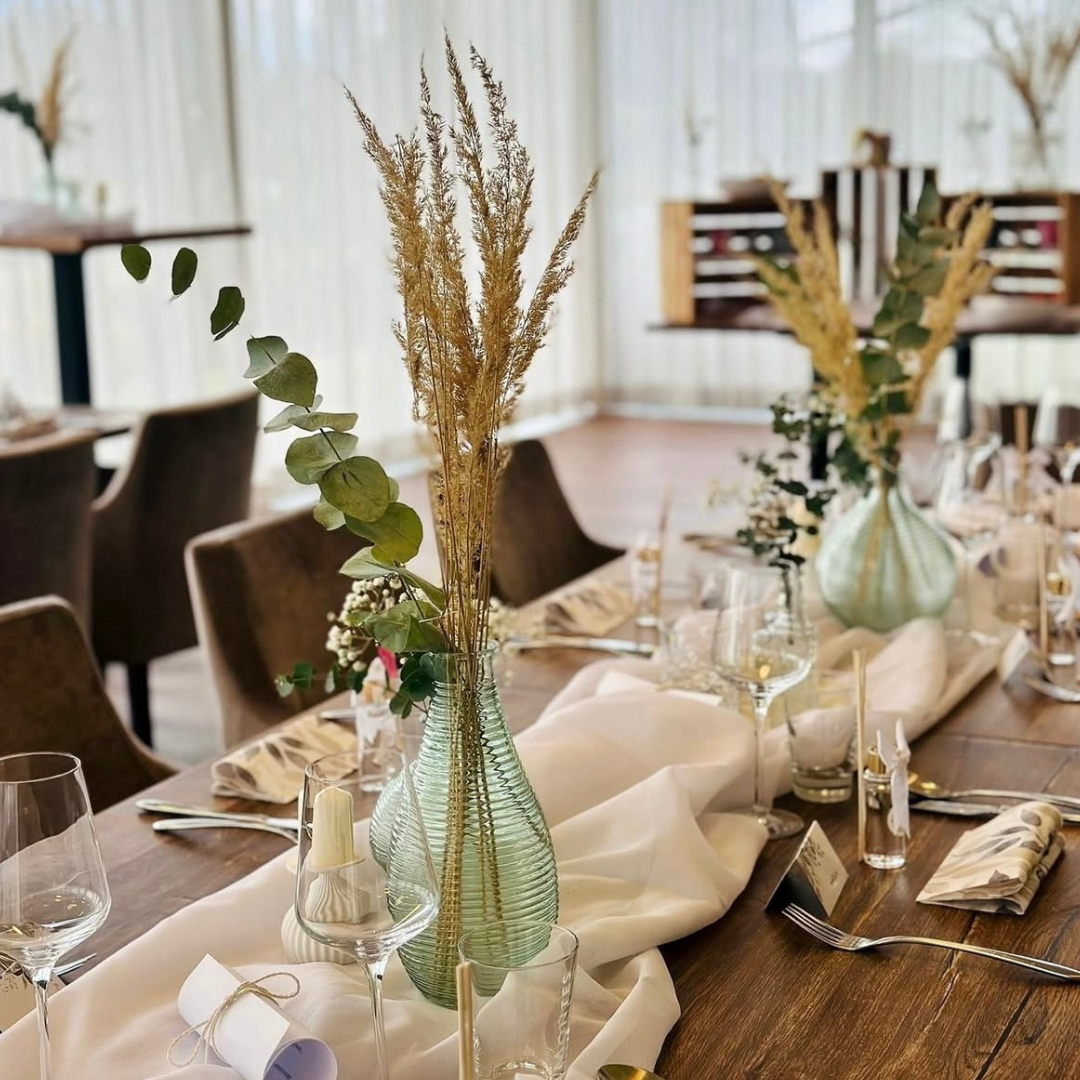 Festlich gedeckter Tisch mit Glasvasen, Trockenblumen und eleganter Tischdekoration im Restaurant Birdie in Wels