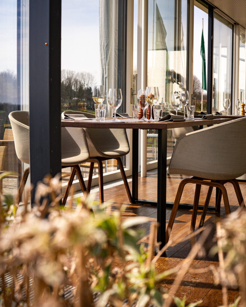 Modern gedeckter Tisch im Wintergarten des Restaurants Birdie in Wels mit Blick ins Grüne