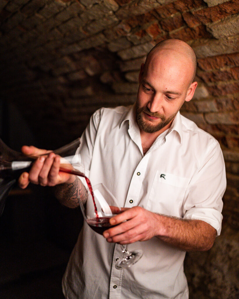 Jürgen Schliessleder schenkt Rotwein in ein Glas im Gewölbekeller des Restaurants Birdie in Wels