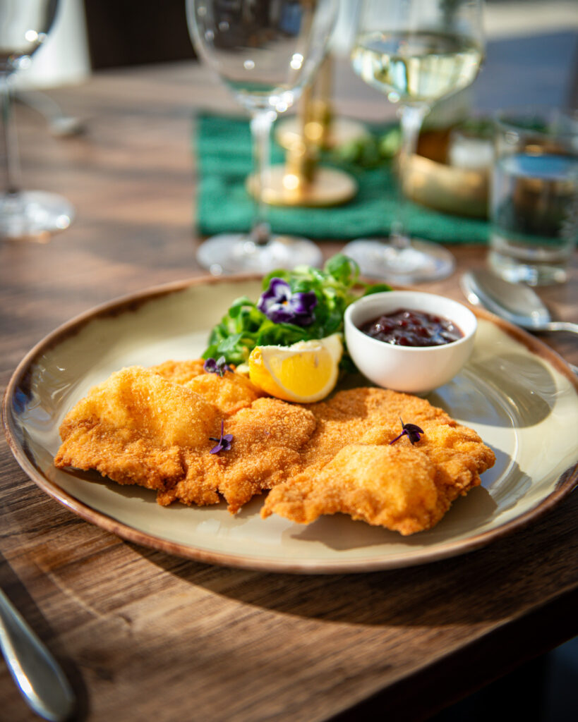 Knuspriges Wiener Schnitzel mit Preiselbeeren und Salat im Restaurant Birdie in Wels